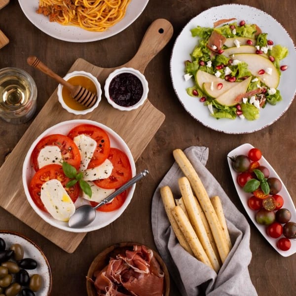 Overhead view of various Italian dishes, including pasta, caprese salad, pear salad, and breadsticks.
