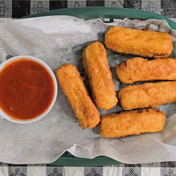 Golden-brown fried mozzarella sticks and a side of red marinara sauce in a basket.