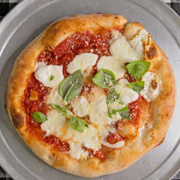 A G's Pizzeria pizza with tomato sauce, fresh mozzarella, basil, and parmesan on a metal tray.
